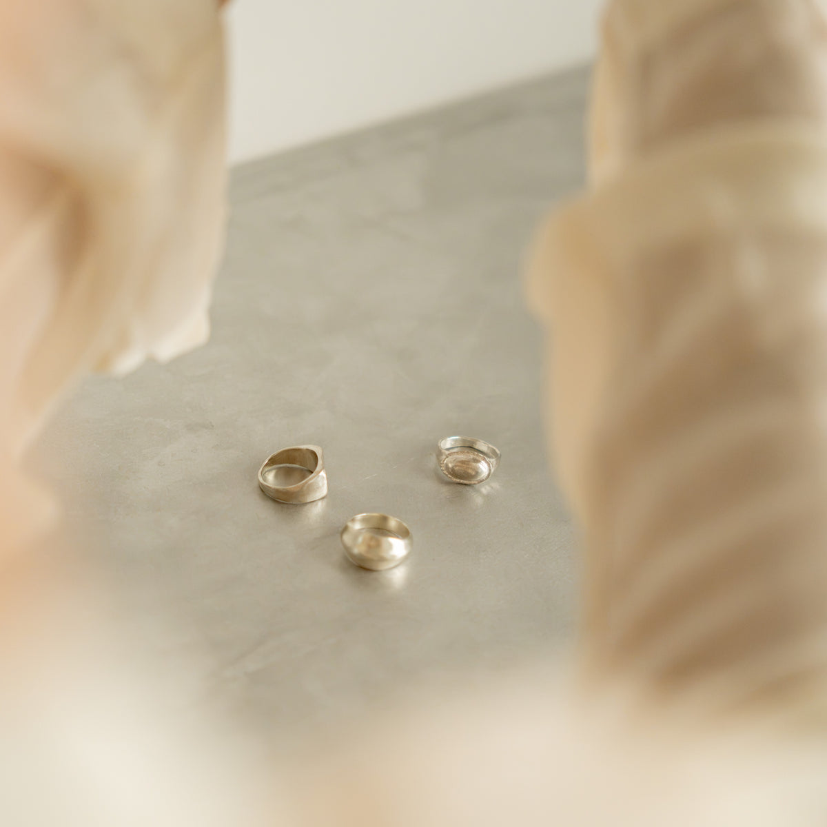 Three sculptural rings on a light work surface.